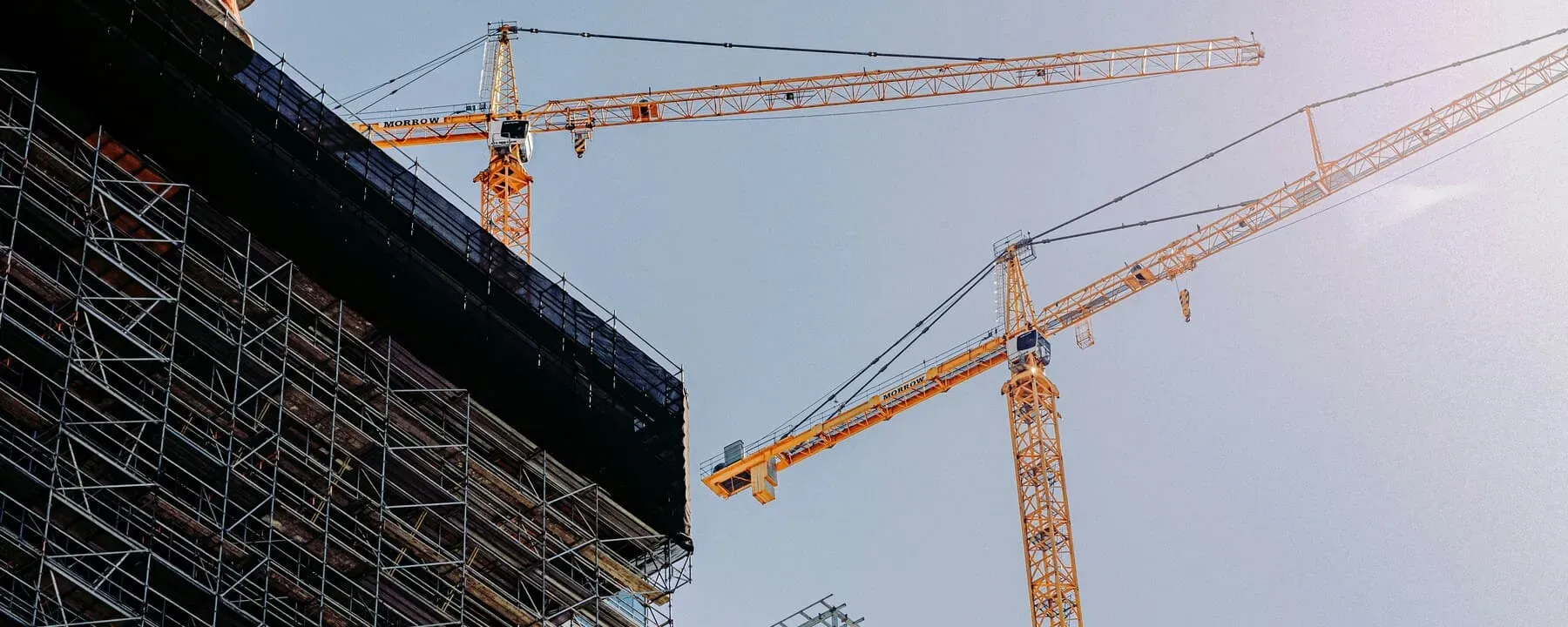 Tower cranes and scaffolding on an active construction project at golden hour