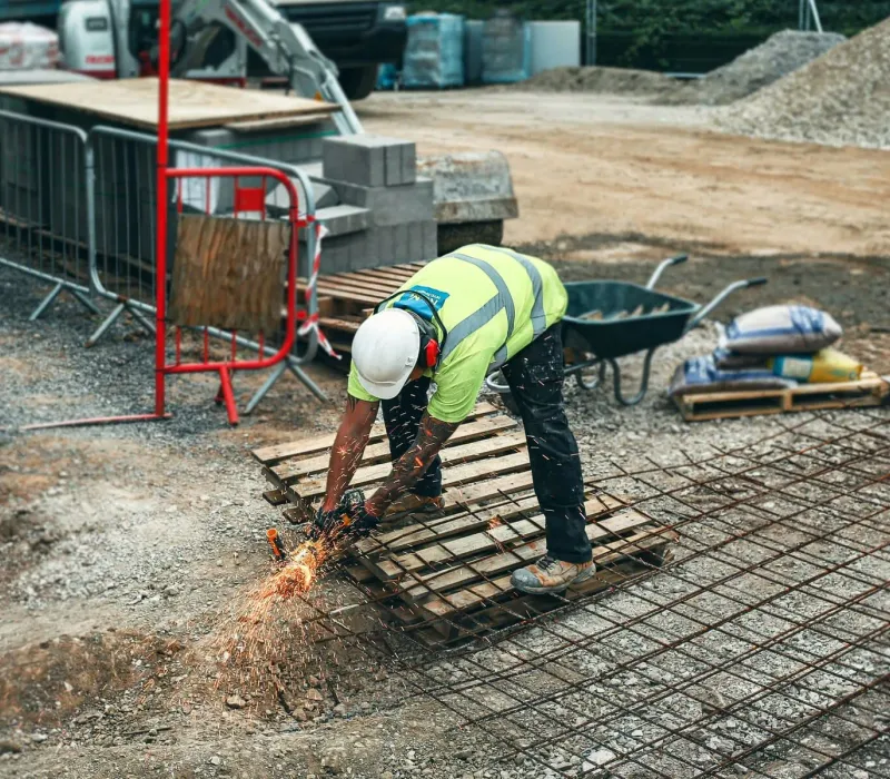Construction worker performing on-site metal cutting during field support