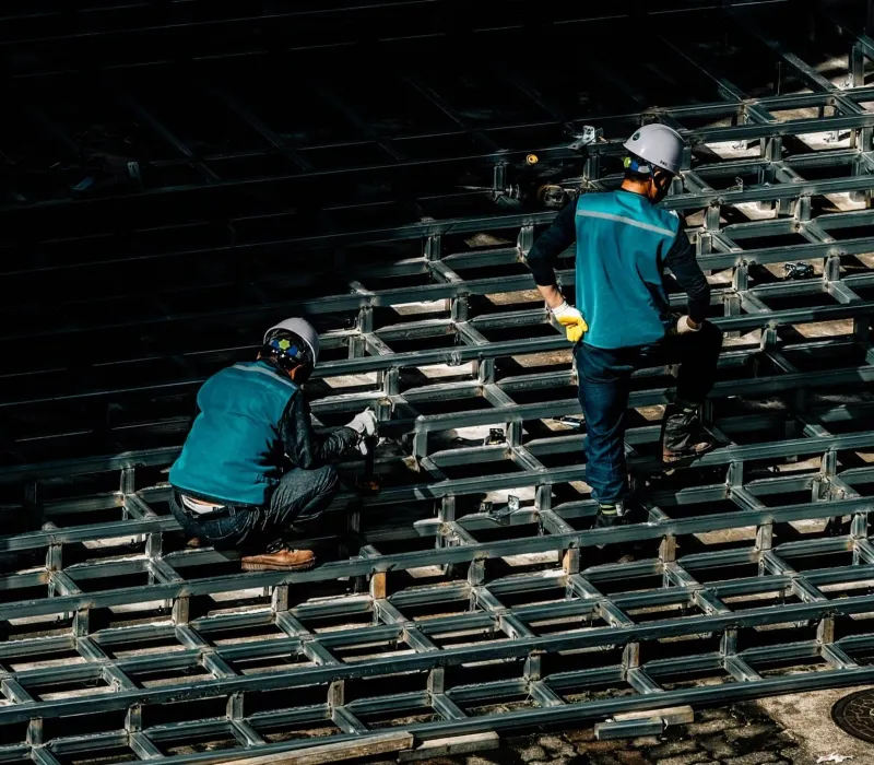 Workers placing and inspecting steel reinforcement on a construction deck