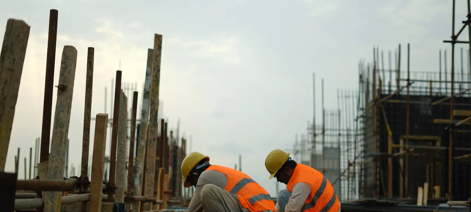 Workers tying reinforcing steel on a deck under overcast sky