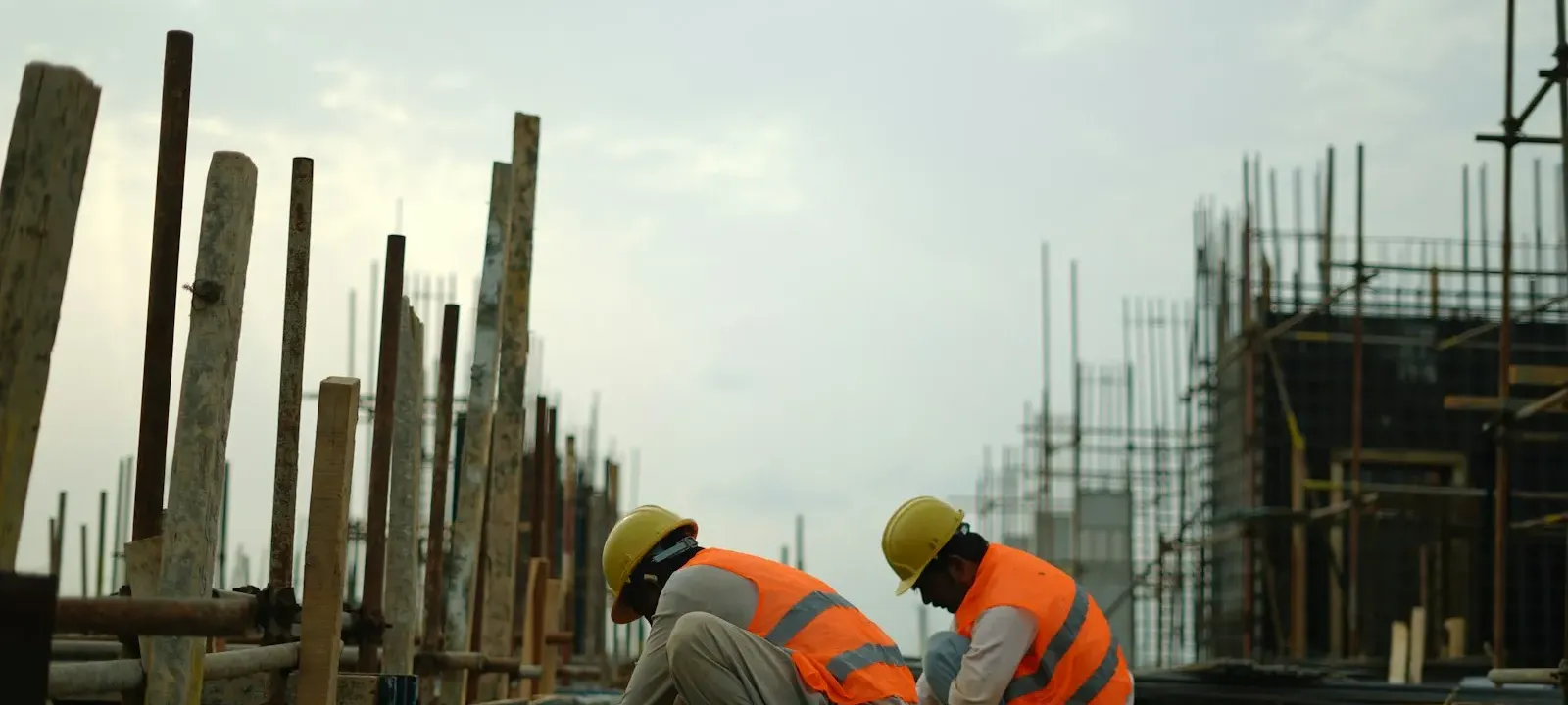 Workers tying reinforcing steel on a deck under overcast sky